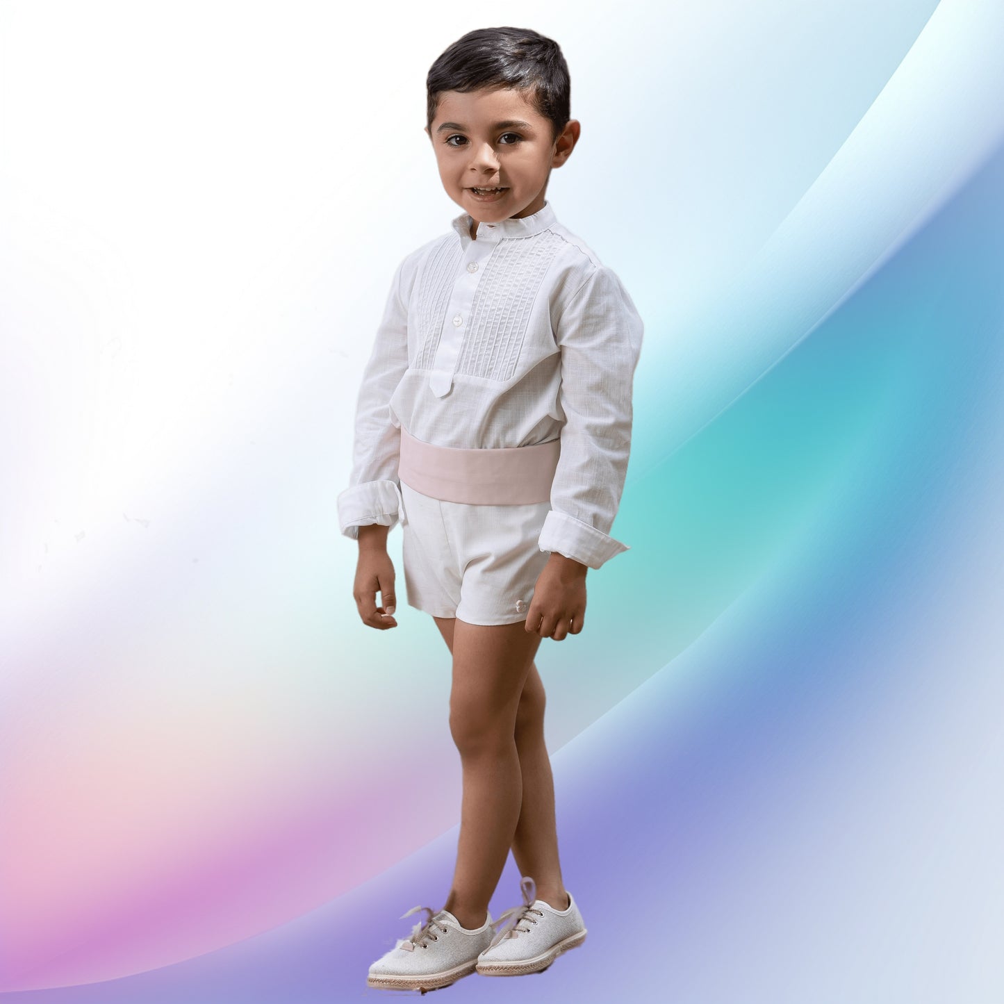 Image of a dapper off-white and pale pink boy's ceremony outfit designed for babies and toddlers. Perfect for events such as weddings, christenings, baptisms, or church gatherings, the handcrafted European-style attire features an off-white shirt and cotton shorts, complemented by a striking pale pink sash, making your little ring bearer look both charming and sophisticated.