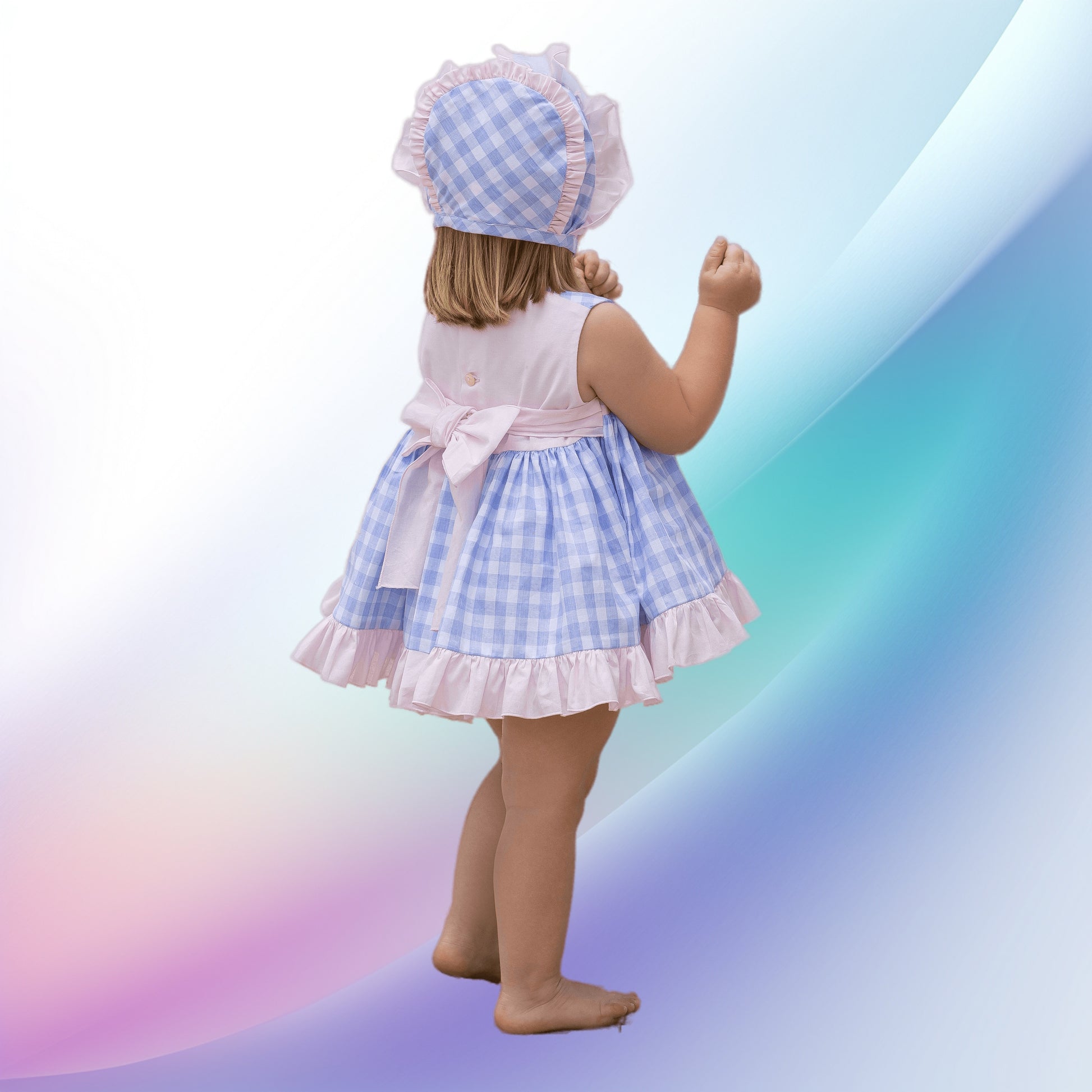 Image of a girls vintage blue gingham dress and diadem by Abuela Tata, perfect for a baby or toddler attending a party or wedding. The lightweight, machine-washable dress features a lavender blue and white check pattern, a charming pink bodice panel with lace and tulle bows, and a large back bow for easy dressing.