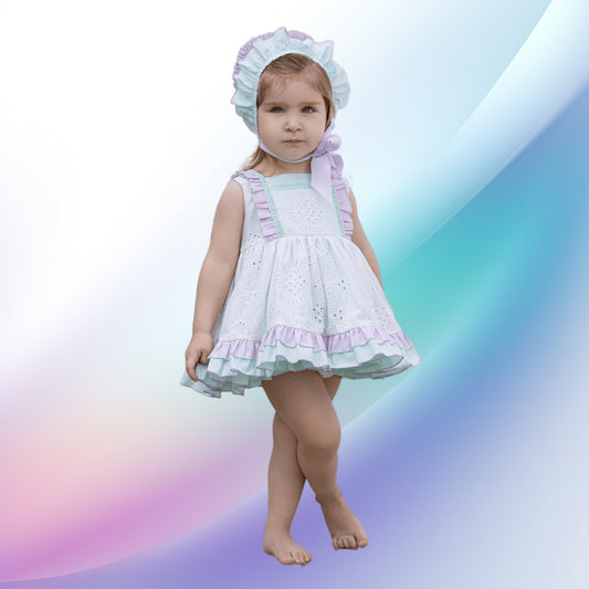 Image of a vintage pastel green and purple dress set by Abuela Tata, perfect for a baby or toddler attending a party or wedding. The soft, lightweight, machine-washable ensemble includes a dress with ruffle trims, stripes, plumeti detailing, and a fixed sash tie, completed by a bonnet and matching knickers.