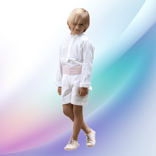 Image of a dapper off-white and pale pink boy's ceremony outfit, ideal for church events, first communions, weddings, or for a ring bearer. The European-style ensemble, handcrafted with care, features an off-white shirt with matching stitch details and cotton shorts, enhanced by a striking pale pink sash.
