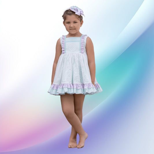 Image of a delightful pastel green and purple girl's dress and diadem by Abuela Tata. Perfect for weddings or parties, the dress features plumeti detailing, ruffle trim, and pearly pink back buttons. Crafted from a soft cotton-polyester blend, it is machine washable and ideal for a flower girl outfit.