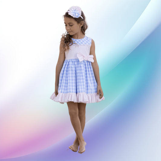 Image of a girls vintage blue gingham dress and diadem by Abuela Tata. Ideal for weddings or parties, this lightweight dress features a lavender blue and white check pattern, pink bodice panel with lace and tulle bows, and a large back bow. The comfortable cotton-linen-polyester blend and easy back zip make it a perfect flower girl outfit.