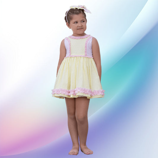 Image of a vintage yellow and pink dress, bonnet, and knickers set by Abuela Tata, perfect for a girl attending a party or wedding. The soft, lightweight, machine-washable outfit features charming ruffle trims, stripes, plumeti detailing, back button fastenings, and a fixed sash tie, making it an ideal flower girl dress.